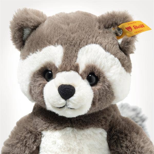 Plush raccoon toy with a visible Steiff tag on a white background, detail shot of face
