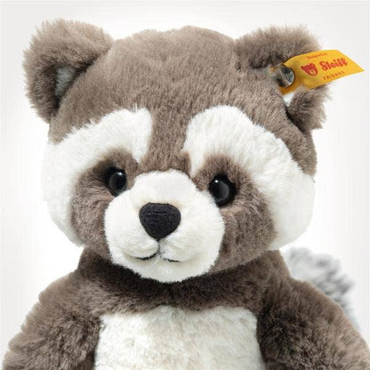 Plush raccoon toy with a visible Steiff tag on a white background, detail shot of face
