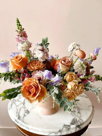 A colorful flower arrangement with roses, ranunculus, spray roses and snapdragons.