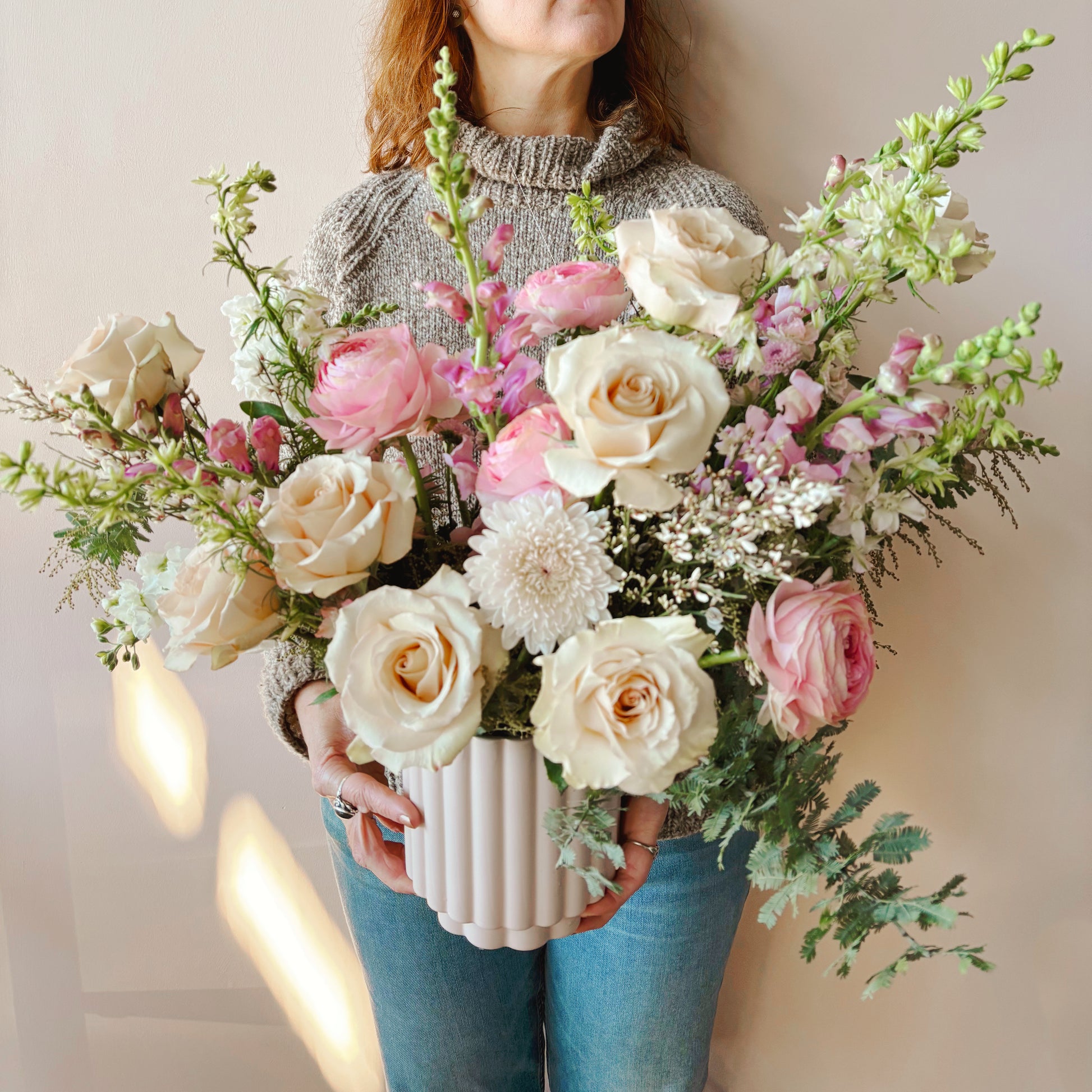 Person holding a large bouquet of flowers against a neutral background