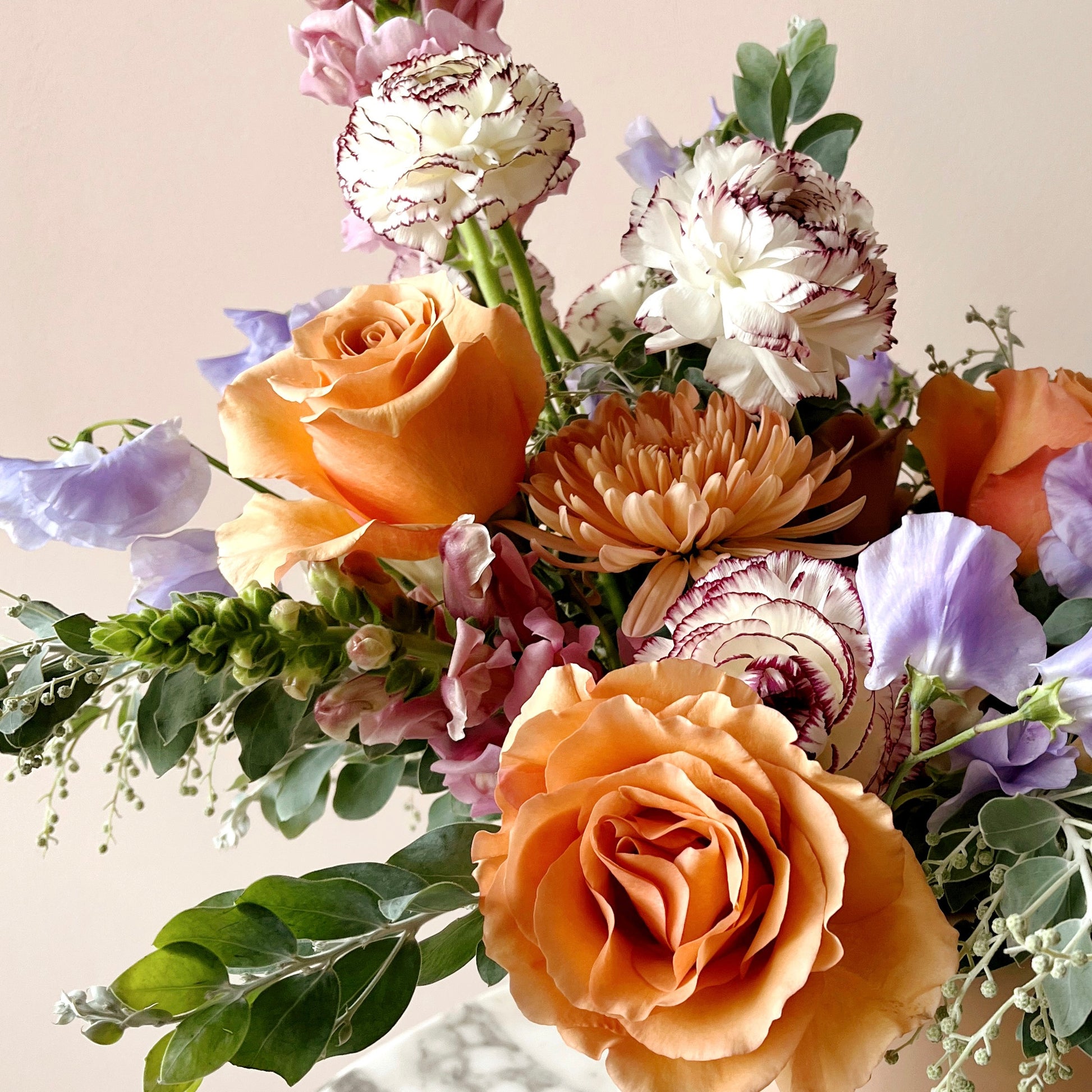 detail image of peach roses and white ranunculus in a flower arrangement