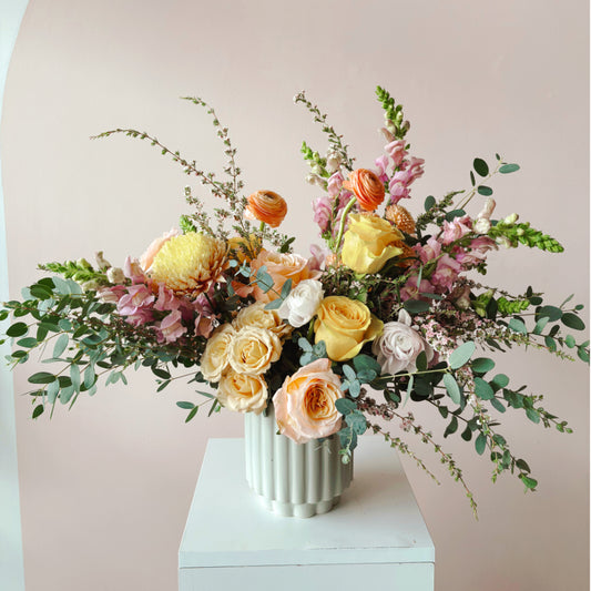A spring floral arrangement featuring roses and ranunculus by bloomstall flowers.