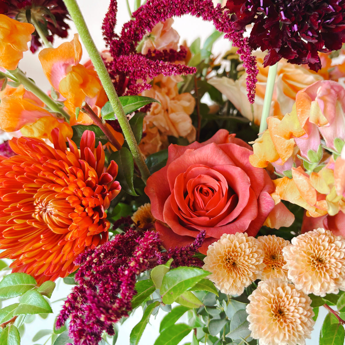 image shows a detailed view of lowers including mums, snapdragons, roses and ranunculus