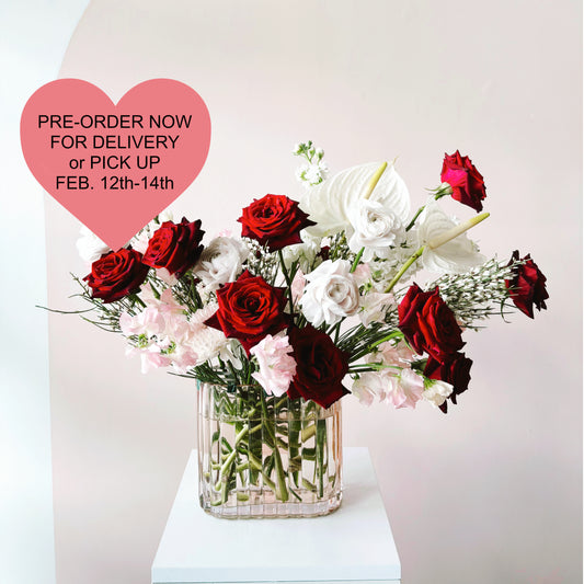 An image showing a dozen roses in red and white with pink accents in a deco inspired vase.