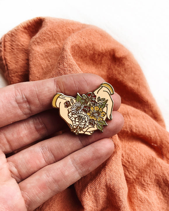 Laura Makes - Hands Offering Flowers Enamel Pin